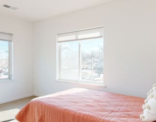 Furnished apartment bedroom with a large window on each wall
