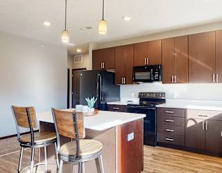 a kitchen with dark brown wooden cabinets and a bar with two chairs