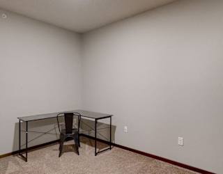Furnished apartment den with work desk and chair in corner of room