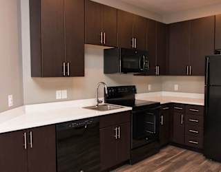 A kitchen with brown cabinets and black appliances.