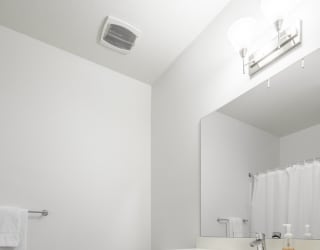 Contemporary bathroom with white cabinetry and white quartz countertops at The Conrad apartments