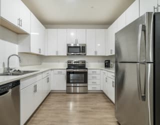 Contemporary kitchen with white cabinetry, quartz countertops and stainless steel appliances at The Conrad