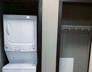 Stacked washer and dryer in closet next to extra storage closet