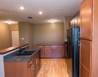 A kitchen with wooden cabinets and a black refrigerator.