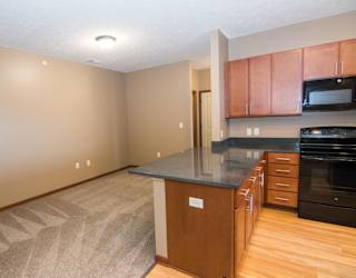 A kitchen with warm brown cabinets and a black countertop.
