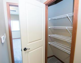Empty linen closet with a white door and shelves.