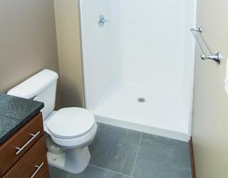 A white toilet sits next to a walk-in shower.