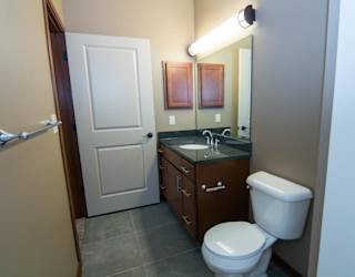 A bathroom with a toilet, sink, and mirror.