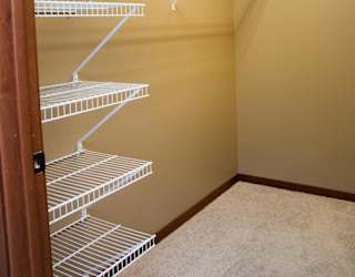 Empty white wire shelves in large walk-in closet
