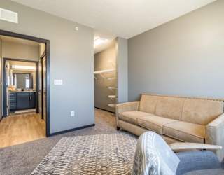 A room with a tan couch and a grey rug.