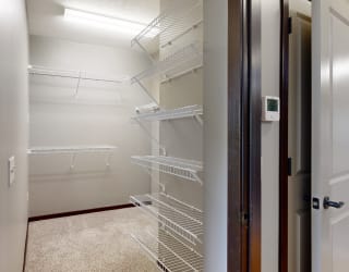 a walk-in closet in the bedroom with lots of shelves