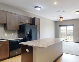 a kitchen with a light granite counter top and a black fridge