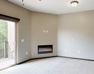 a carpeted living room with an electric fireplace