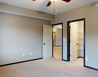 a bedroom with a ceiling fan and a door to walk in closet
