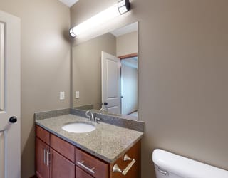 the primary bathroom with a light granite vanity and overhead lighting