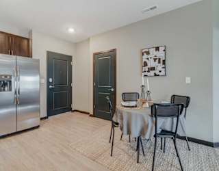 A kitchen with a table and chairs set up in front of it, next to the front entryway