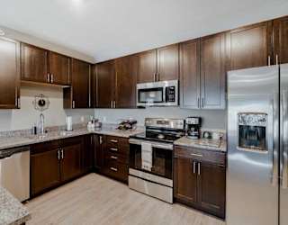 A modern kitchen with brown cabinets and stainless steel appliances