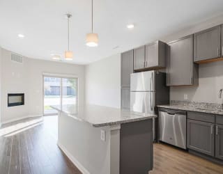 a open-concept kitchen with stainless steel appliances and granite counter tops next to a living room