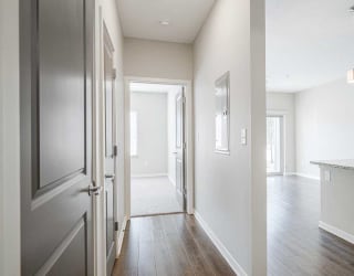 a hallway with a door open to a bedroom next to a kitchen and living room
