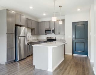 an open kitchen with stainless steel appliances, grey cabinets, and granite counter tops