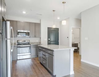 an open-concept kitchen with a large island next to a hallway