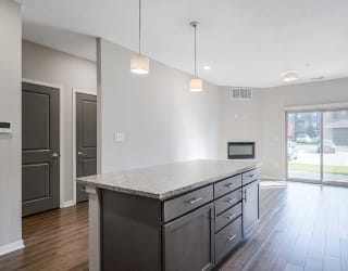 a kitchen with an island next to an open living room and a doorway to the hall