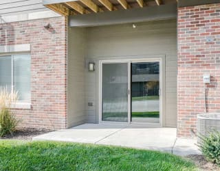 the sliding glass door of a first floor Lilac apartment with a patio space