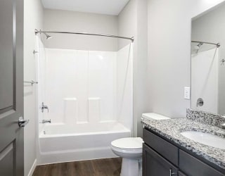a bathroom with a sink with granite countertop and a tub shower