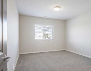 a bedroom with carpeting and natural light from a large window