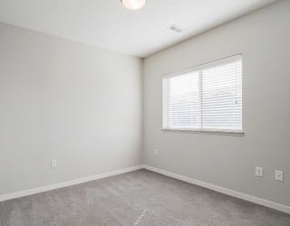 a bedroom with carpeting and a large window for natural light