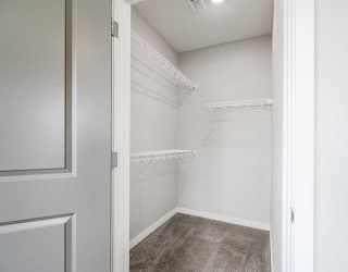 a walk-in closet for the second bedroom with built-in shelves