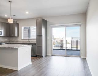 an open kitchen and dining room with a door to a balcony