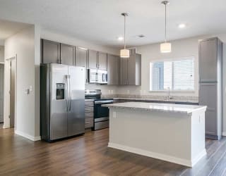 a kitchen with stainless steel appliances, grey cabinets, and a large island