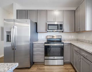 a kitchen with stainless steel appliances, grey cabinets, and granite counter tops