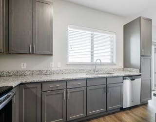 a kitchen with stainless steel appliances, grey cabinets, and granite counter tops
