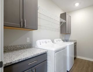 a large laundry room with a full-sized washer and dryer with over head shelving and cabinet storage