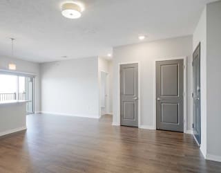 an open living room and dining room next to a hallway leading to the primary bedroom