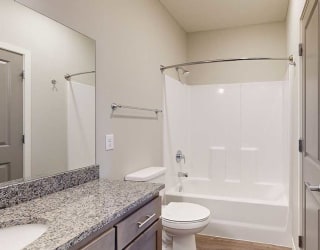 a bathroom with a tub shower and a granite counter top vanity sink