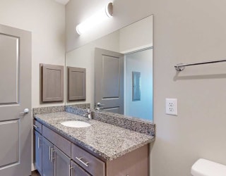 a bathroom with a large vanity sink with granite countertop and a mirror