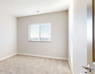 a bedroom with a large window and carpeting