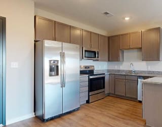 a kitchen with stainless steel appliances, grey wooden cabinets, and a peninsula countertop