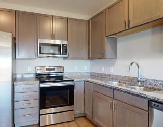 a kitchen with stainless steel appliances and grey wooden cabinets