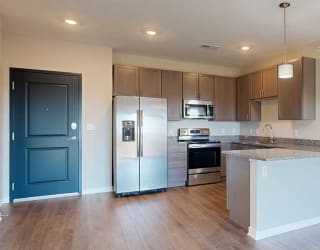 a kitchen with grey cabinets and granite countertops featuring stainless steel appliances