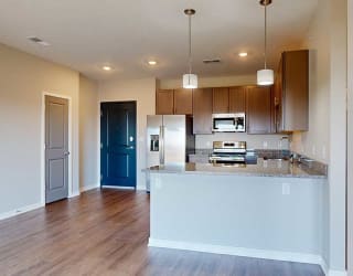 a kitchen with grey wooden cabinets next to an entry way with a coat closet