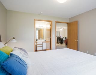 Furnished bedroom with a bed and a door to a bathroom and living area