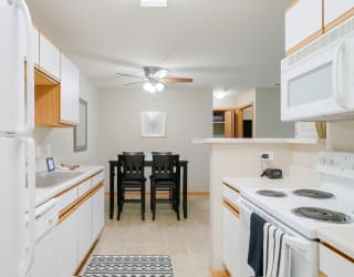 a kitchen with white appliances and a dining room table with chairs in the back