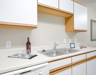 a kitchen with a sink and a bottle of wine on the counter