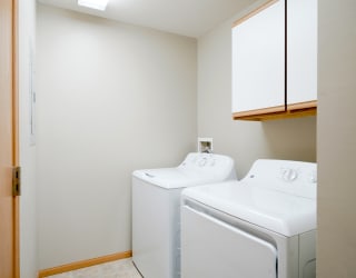 the laundry room has a washer and dryer and cabinet for storage