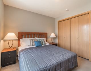 room with bed, 2 nightstands with lamps, and bifold closet doors