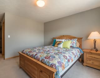 room with bed and one nightstand with lit lamp